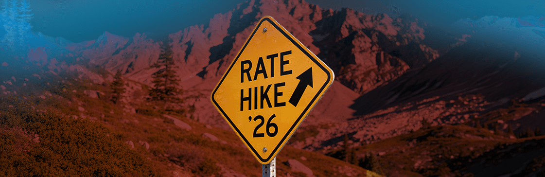 A road warning sign reading "Rate Hike '26" with an upward arrow, set against a mountain backdrop — illustrating market expectations for a Fed rate hike in 2026.